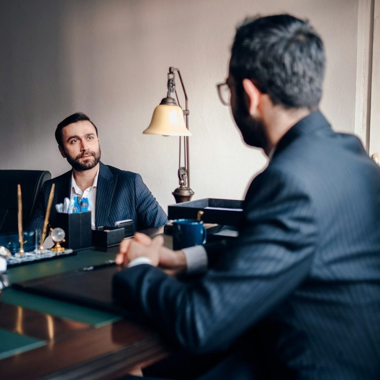 Consultation professionnelle entre deux hommes en costume, illustrant l’écoute et l’accompagnement sur mesure